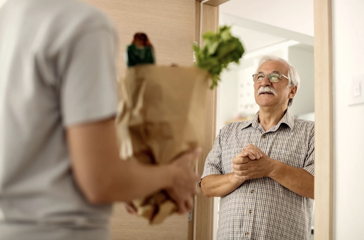 Happy senior receiving groceries at home
