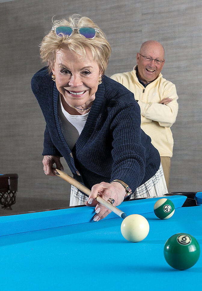 Senior Couple Playing Pool At Searstone Retirement Community In Cary, North Carolina