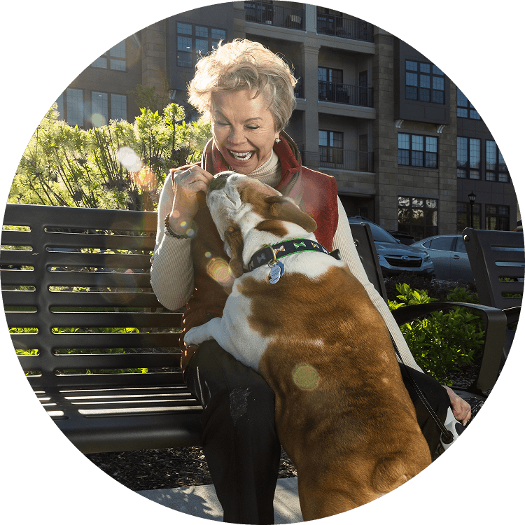 Senior woman giving her dog a treat outside of Searstone