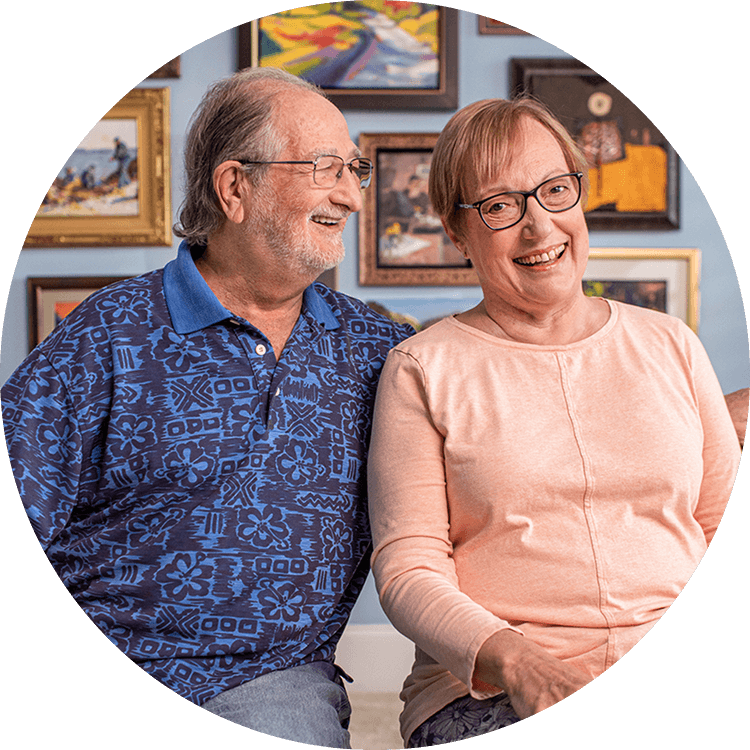 A senior couple smiling as they are seated in their senior living home