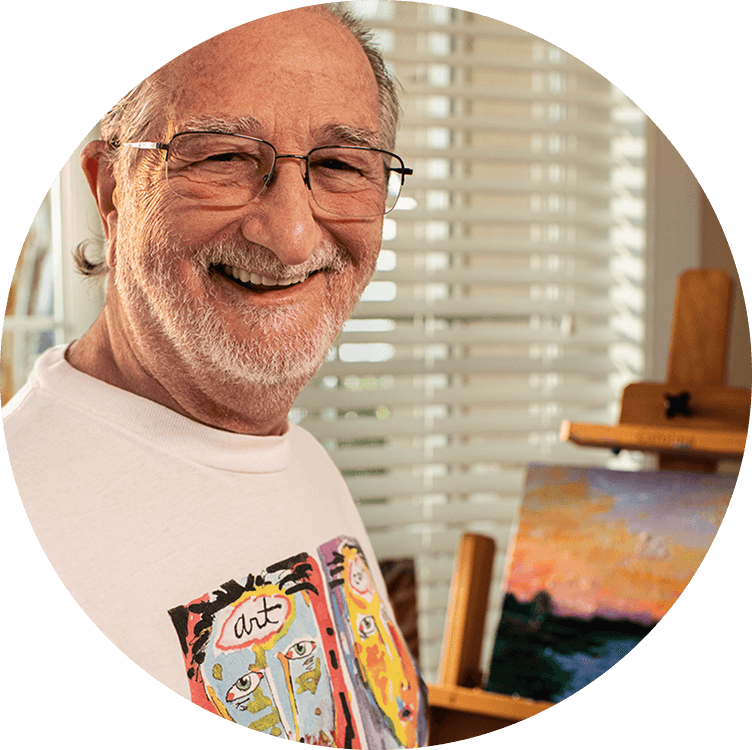 A senior male smiling as he is painting