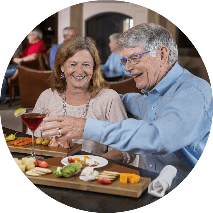 Elderly couple enjoying food and drinks in a senior living dining area