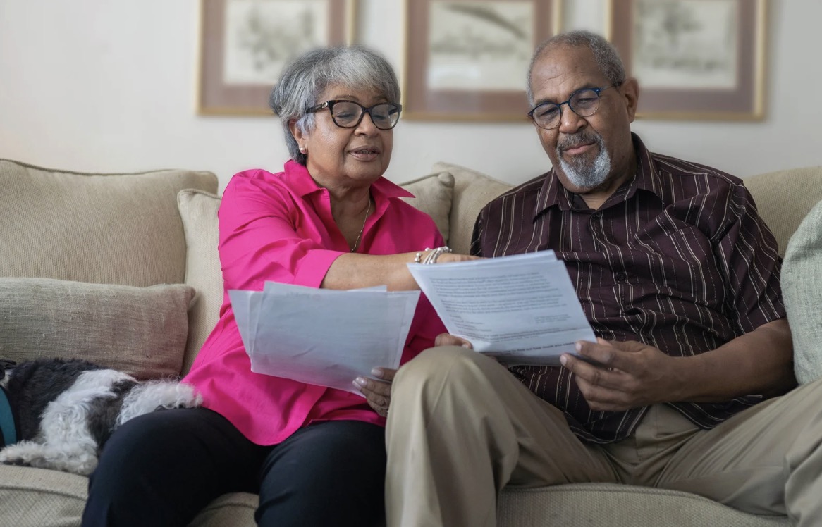 Senior couple sitting together on a couch reviewing paperwork